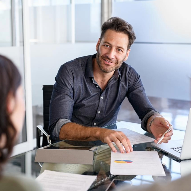 Claims advisor discussing paperwork and claims with a colleague in a glass-walled office.
